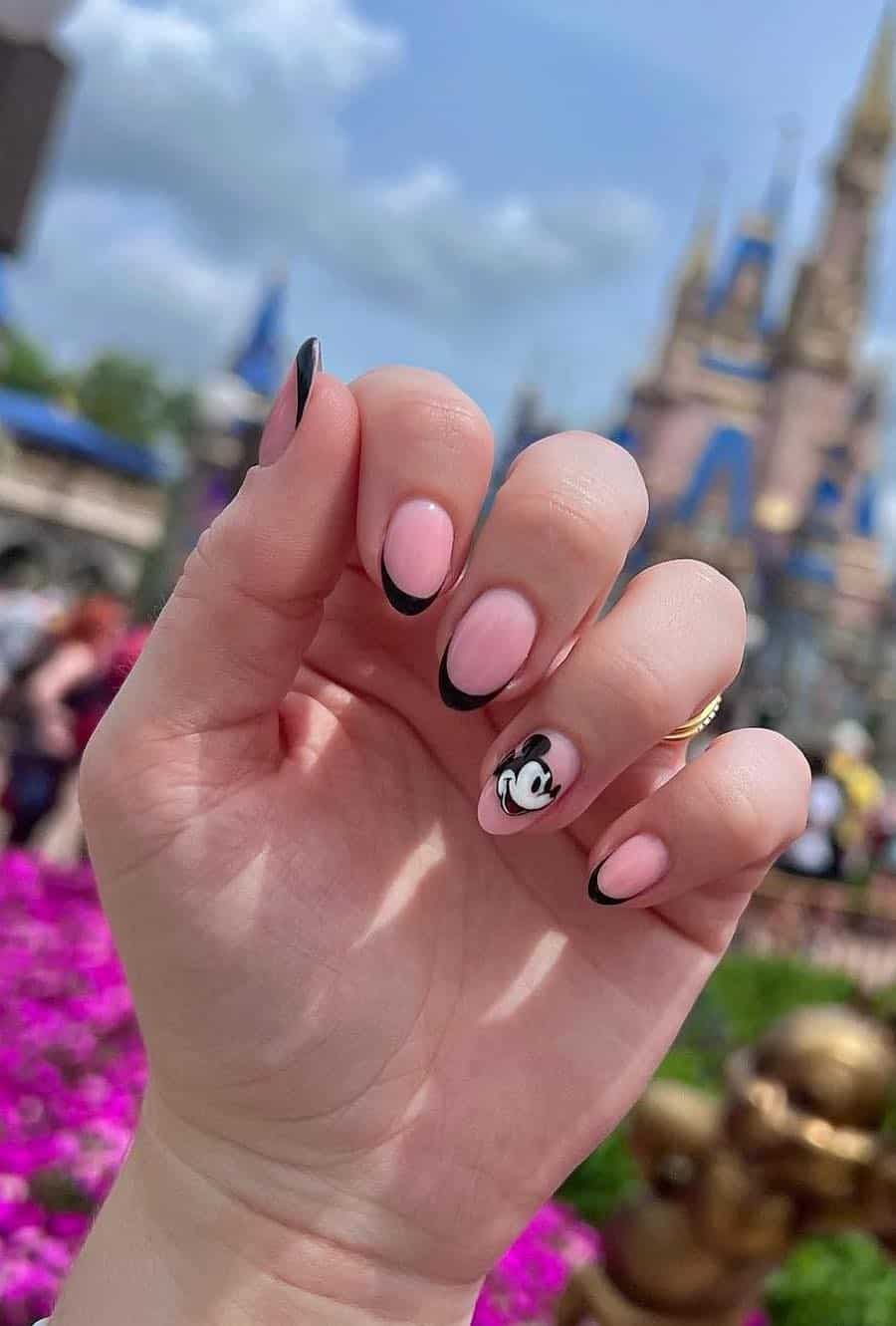 Medium almond nails with a Mickey Mouse design featuring soft pink polish, black tips, and Mickey nail art