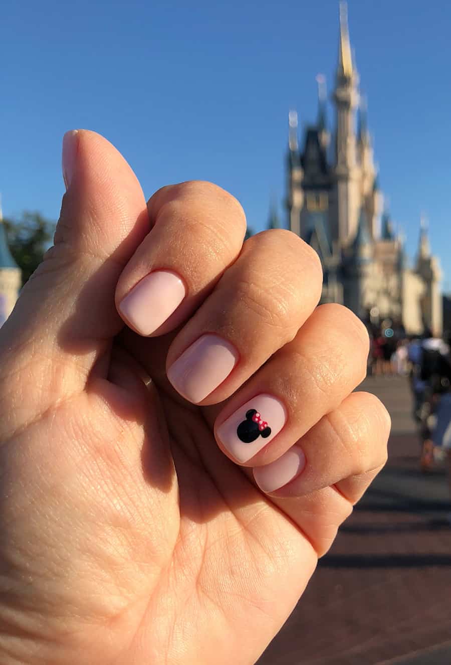 Short squoval nails with a Minnie Mouse design featuring a nude polish base