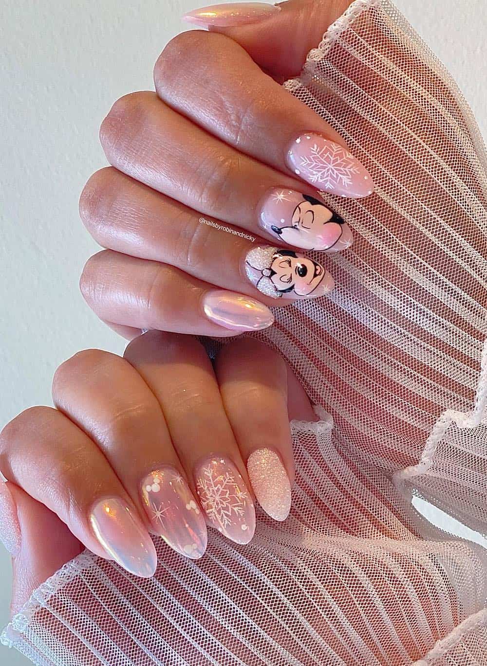 Medium almond nails with a Christmas Mickey Mouse design featuring soft pink chrome polish and snowflake details