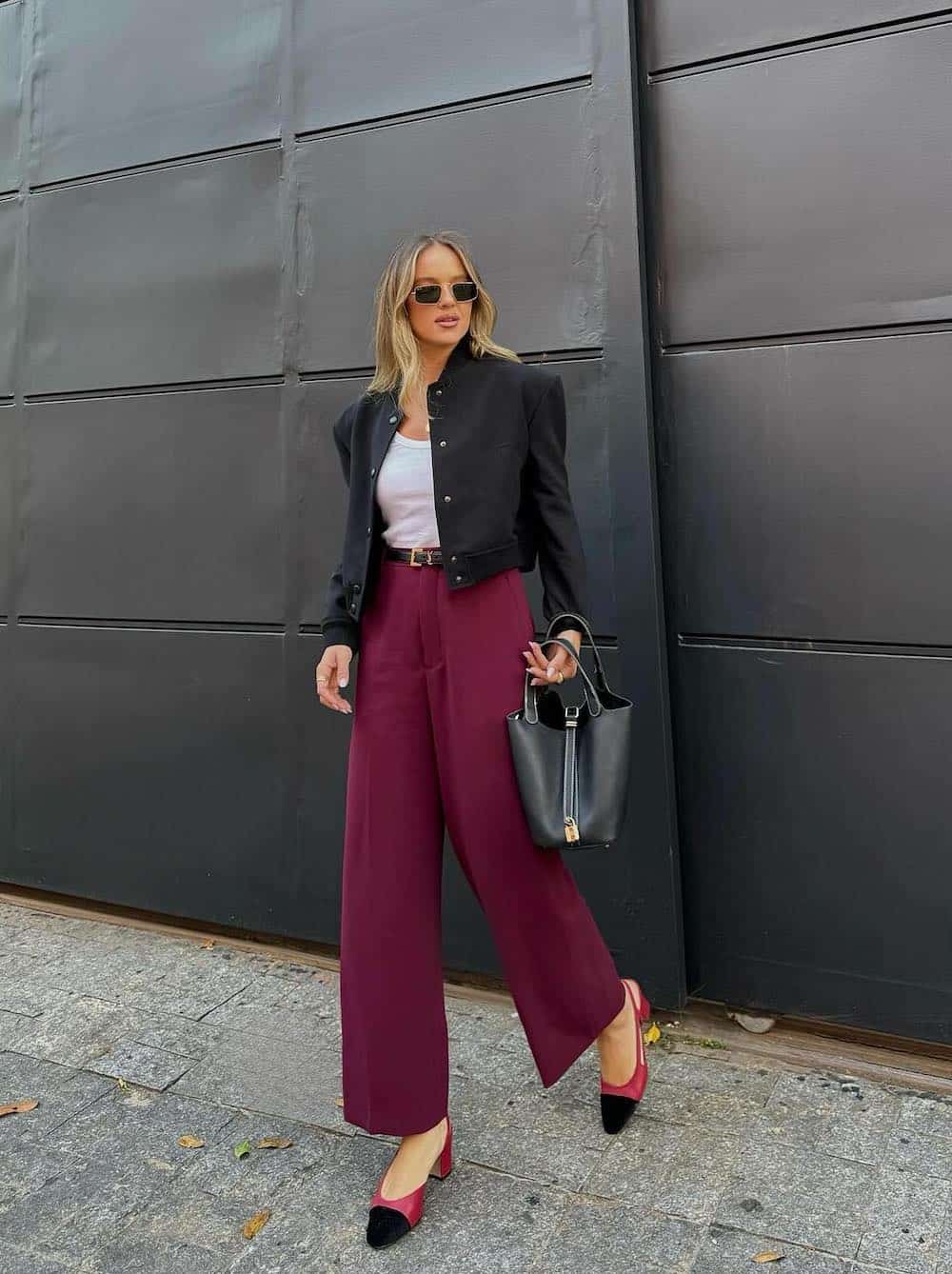 Woman wearing burgundy pants, a white tank, a black cropped blazer and red and black Mary Jane heels.