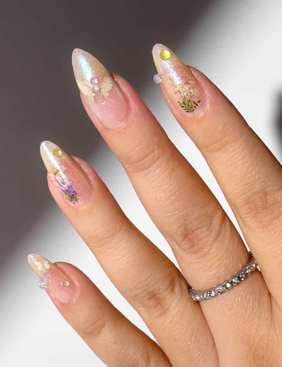 Long almond nails painted in shimmering gold polish with fairy core nail stickers and gems