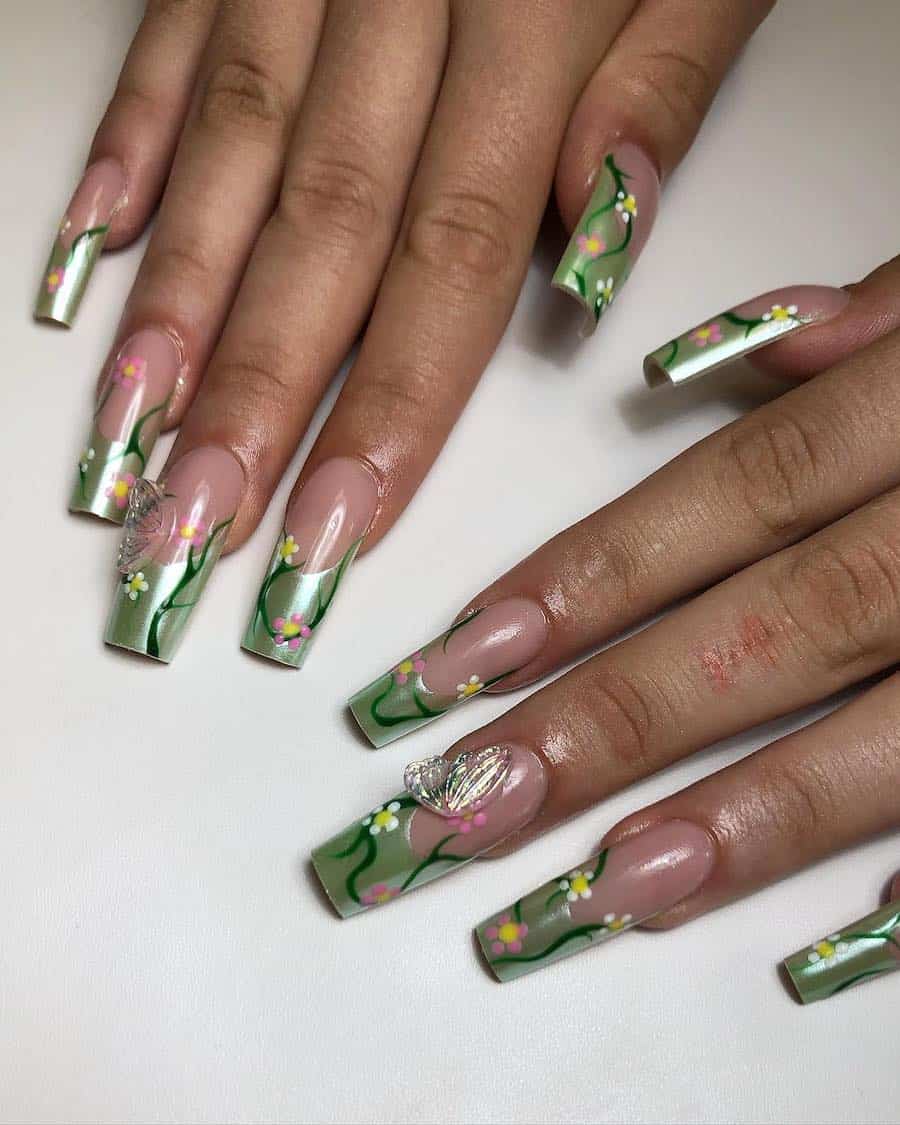 Long square nails with light green chrome tips, floral details, and fairy wing charms