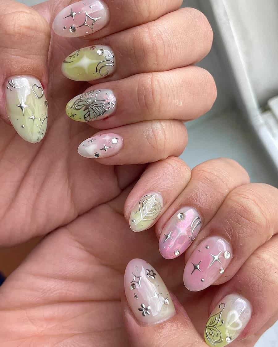 Short almond nails painted in shimmering pink, yellow, and white colors with silver fairy core nail art