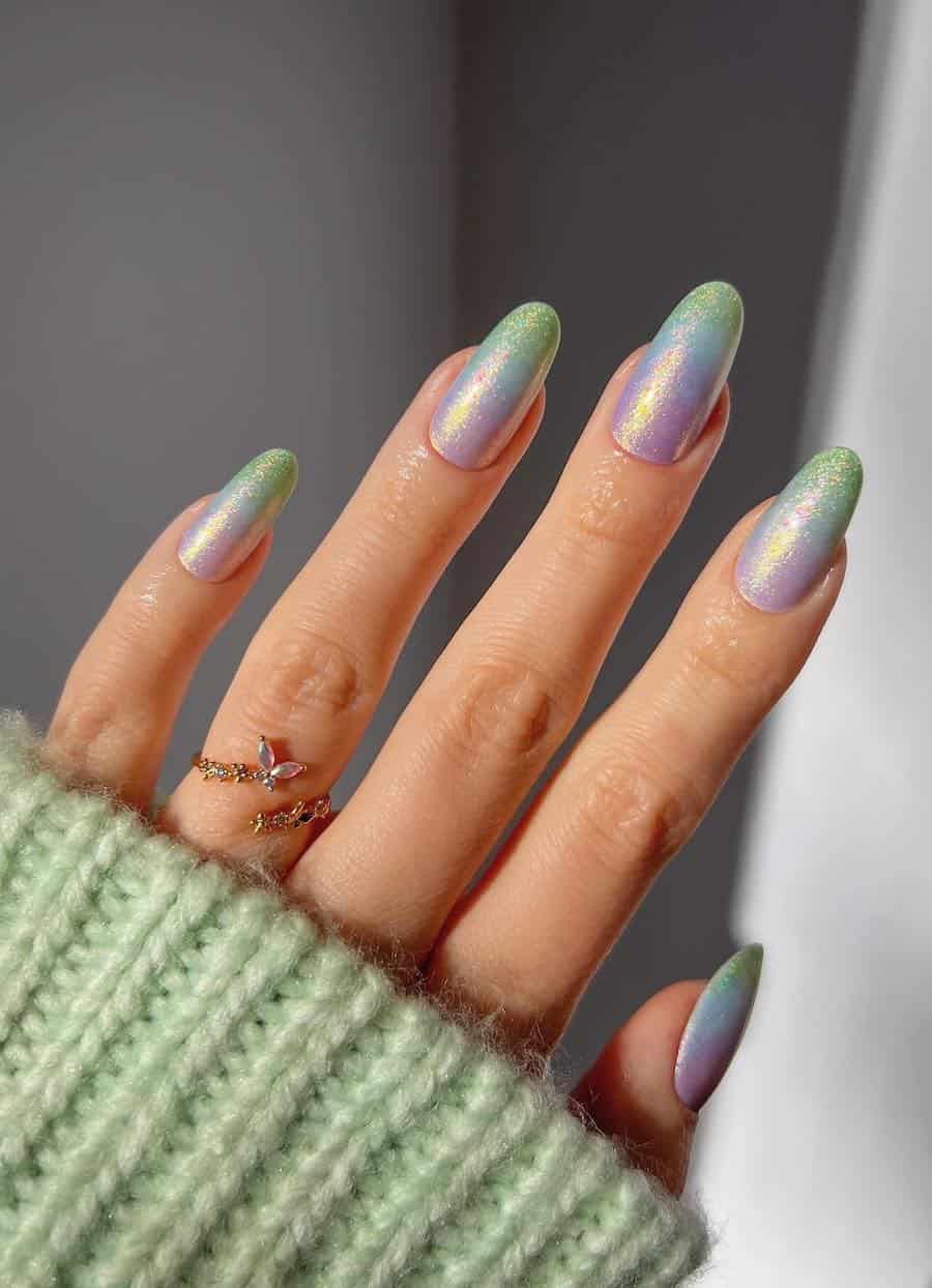Long round nails painted a shimmering ombre featuring purple, blue, and green