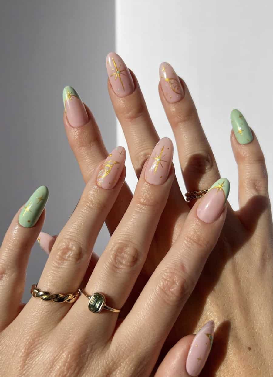 Medium round nude nails with gold sparkles and wing nail art with accents of light green polish