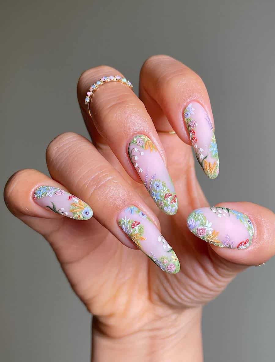 Long almond nails with a matte light pink base and fairy core nail art featuring floral art and mushroom accents