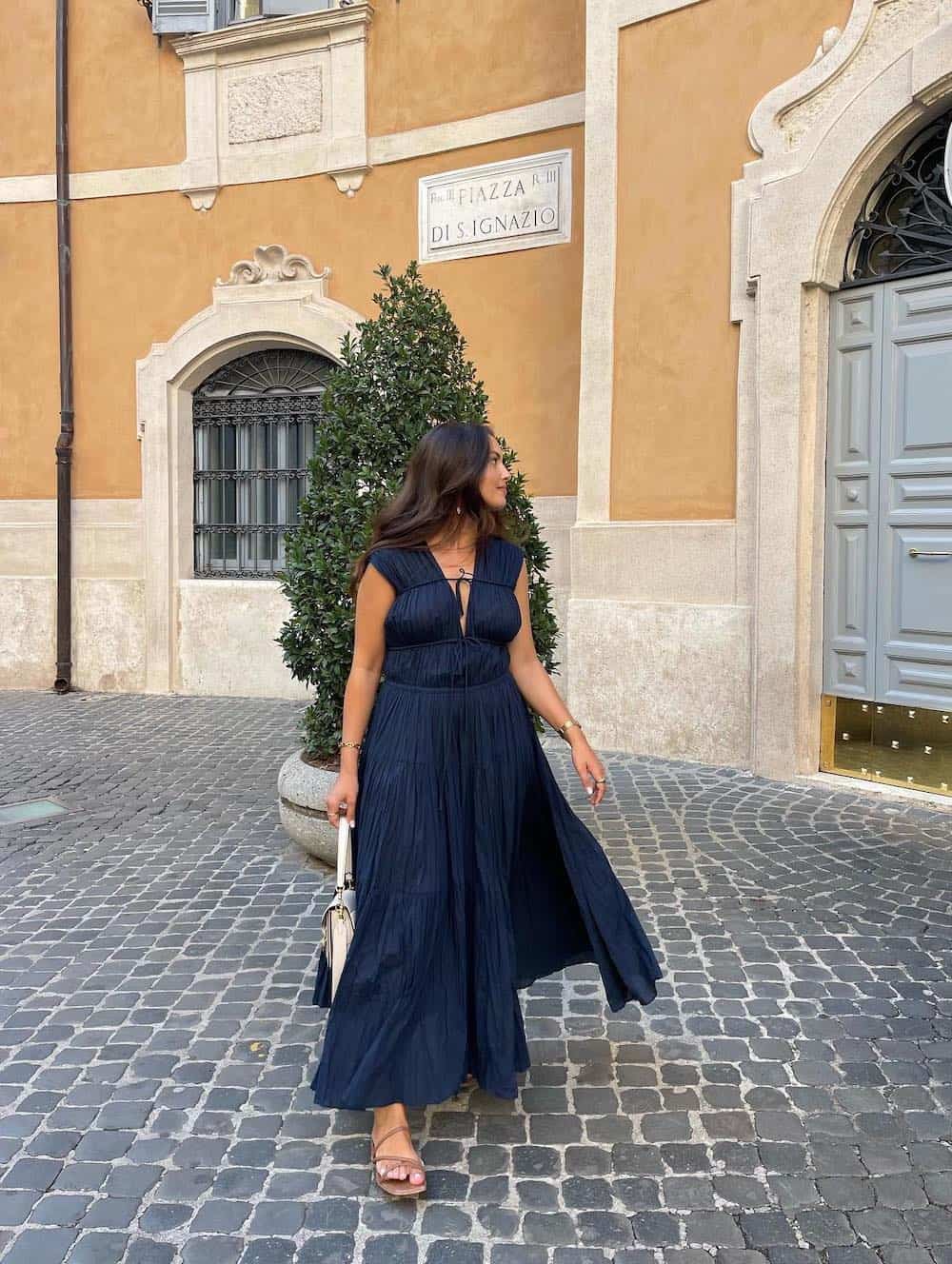 Woman wearing a navy blue maxi dress with brown sandals.