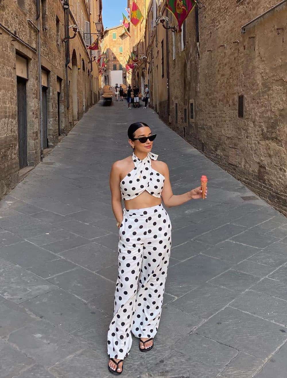 Woman wearing a black and white polka dot pant set with black sandals.