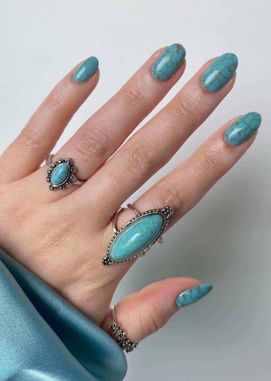 Short round nails featuring turquoise nail art