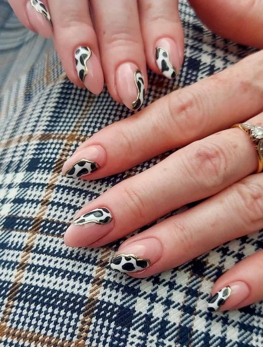 Short nude almond nails featuring cow print waves and gold borders