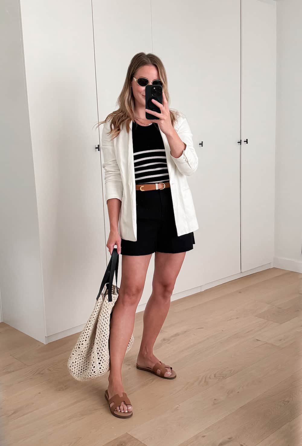 Christal wearing black shorts, a black and white striped sweater, a white blazer and tan sandals.
