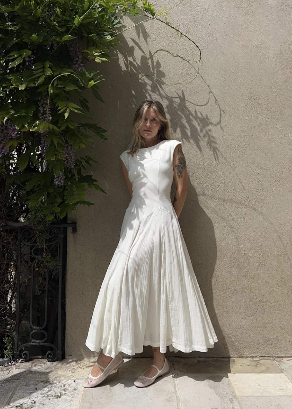 a woman wearing a white maxi dress with sheer ballet flats