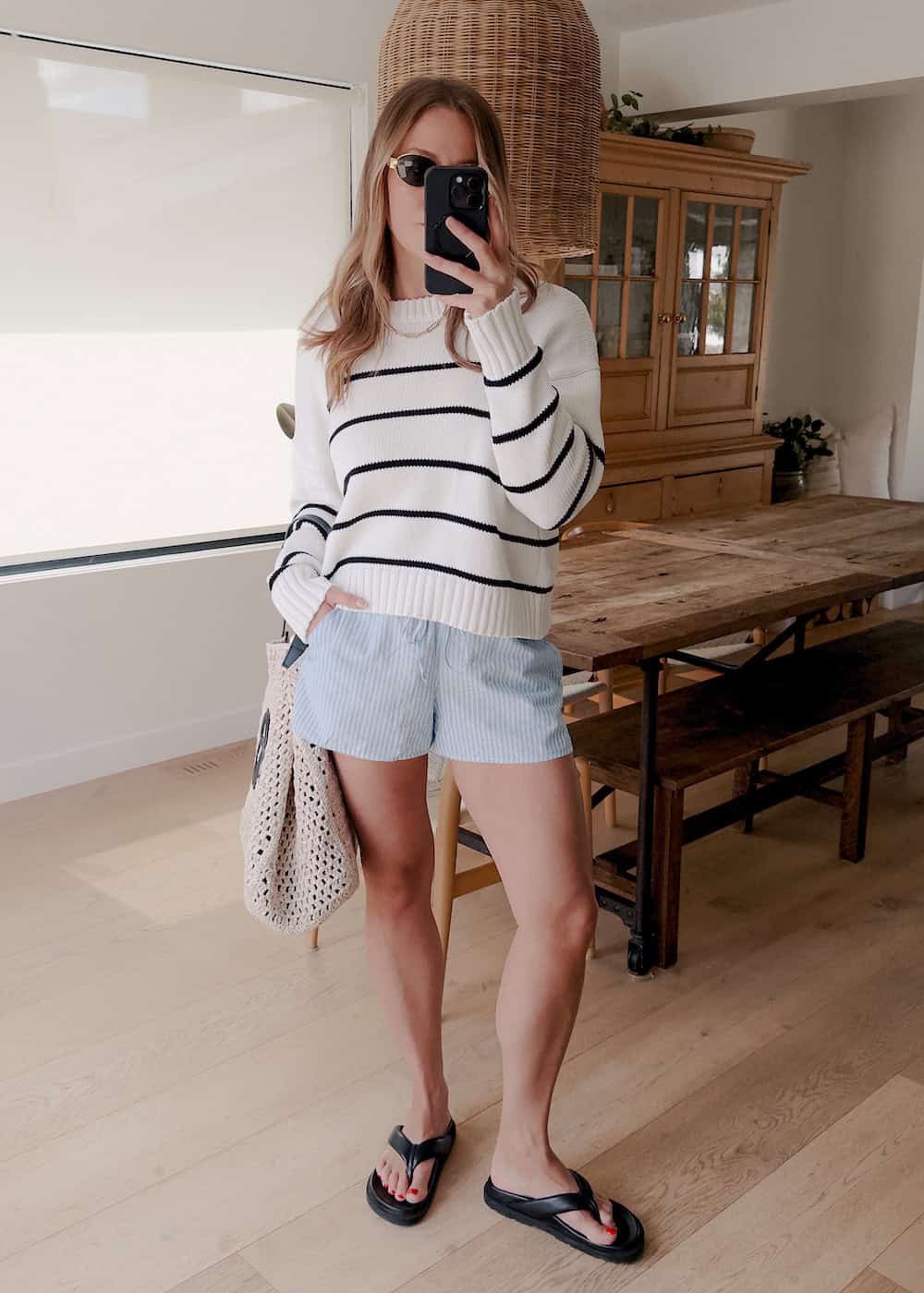 a woman wearing blue and white striped shorts and a black and white striped crewneck sweater