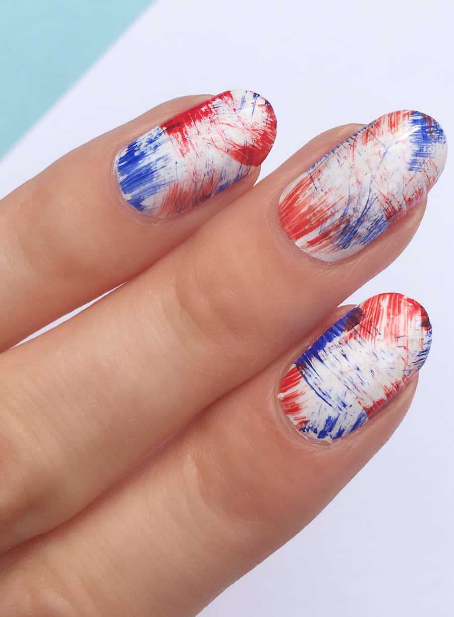short round white nails with streaks of red and blue nail polish