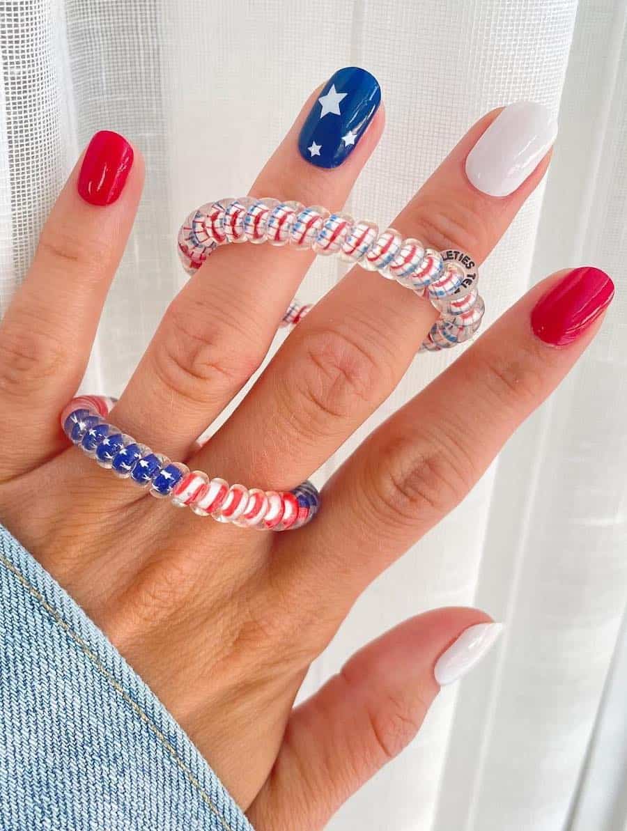 short squoval nails featuring red and white nails polish and a blue accent nail with white stars