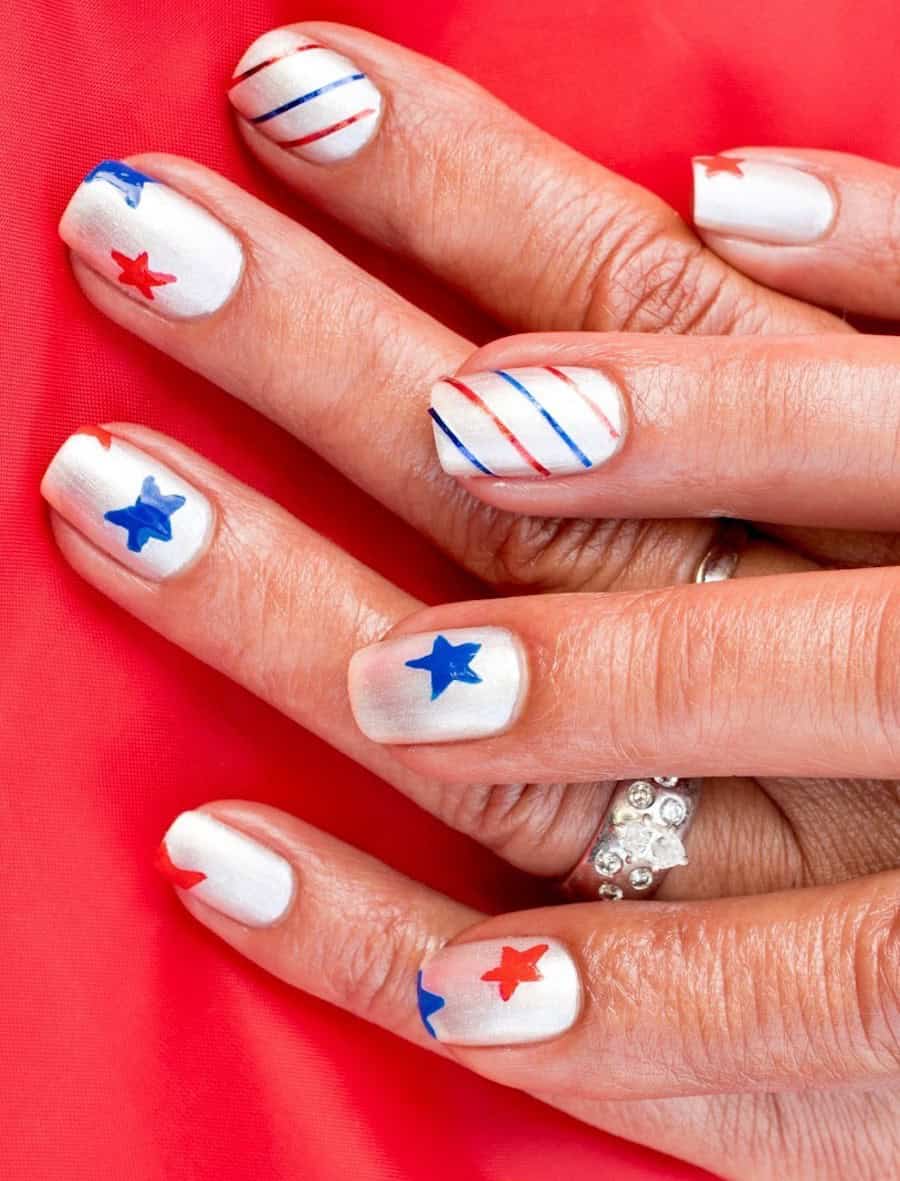 short square nails with metallic white nail polish and red and blue stars and stripes
