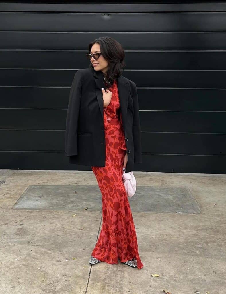 woman wearing an oversized black blazer over a maxi floral red dress with studded flats