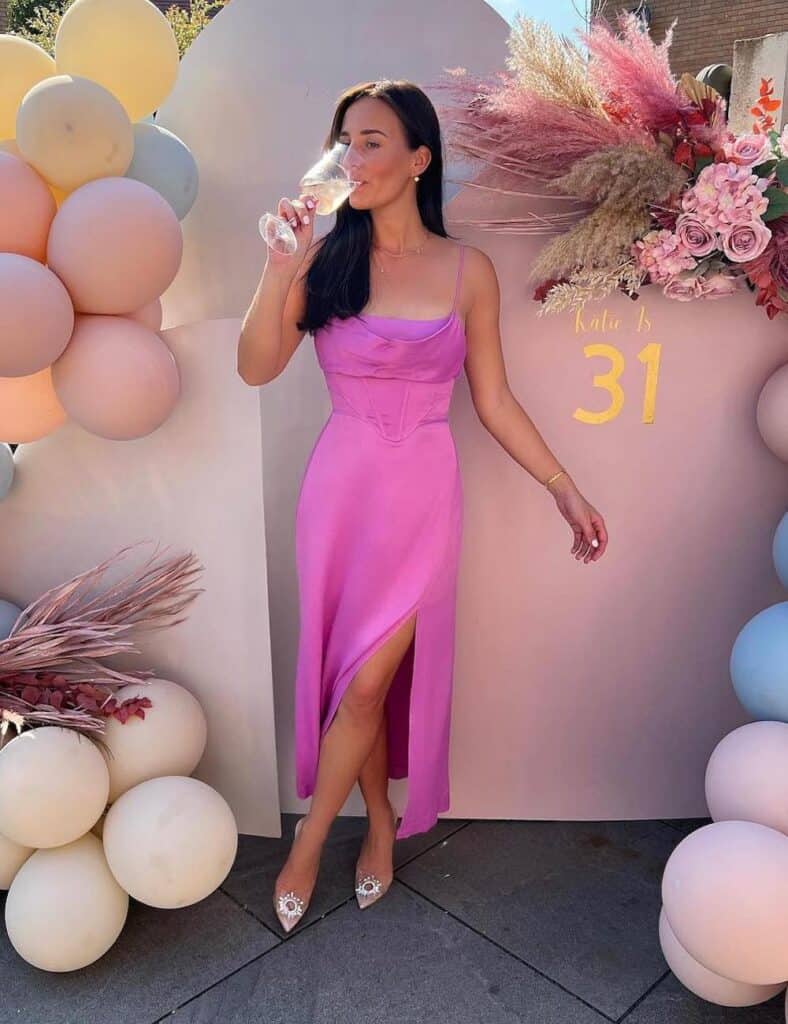 woman wearing a pretty pink silk slip dress and heels for her birthday