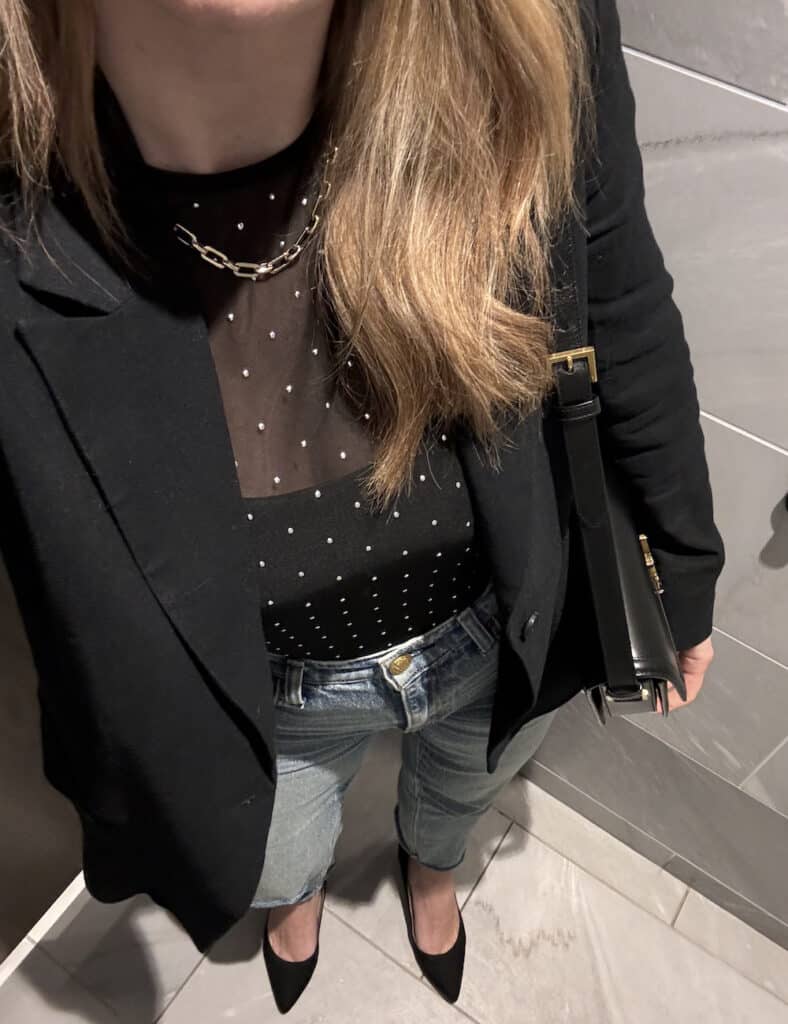 woman wearing a black sheer top with stud details and jeans