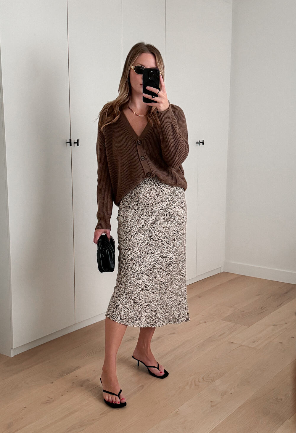 Christal wearing a printed slip skirt with a brown cardigan and black accessories.
