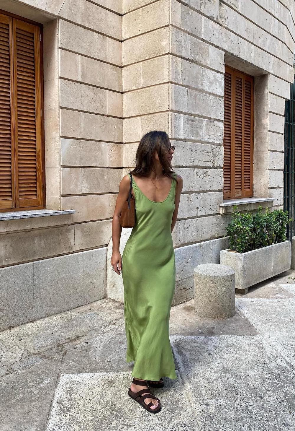 Woman wearing a green silk slip dress with sandals.