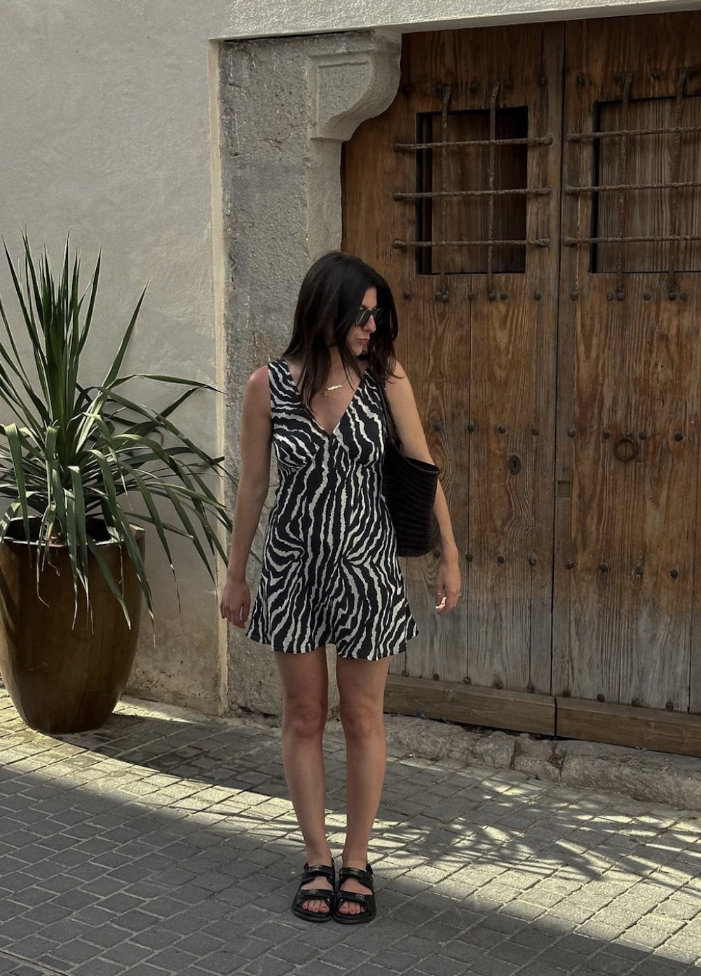 Woman wearing a black and white animal print romper with black Birkenstocks.