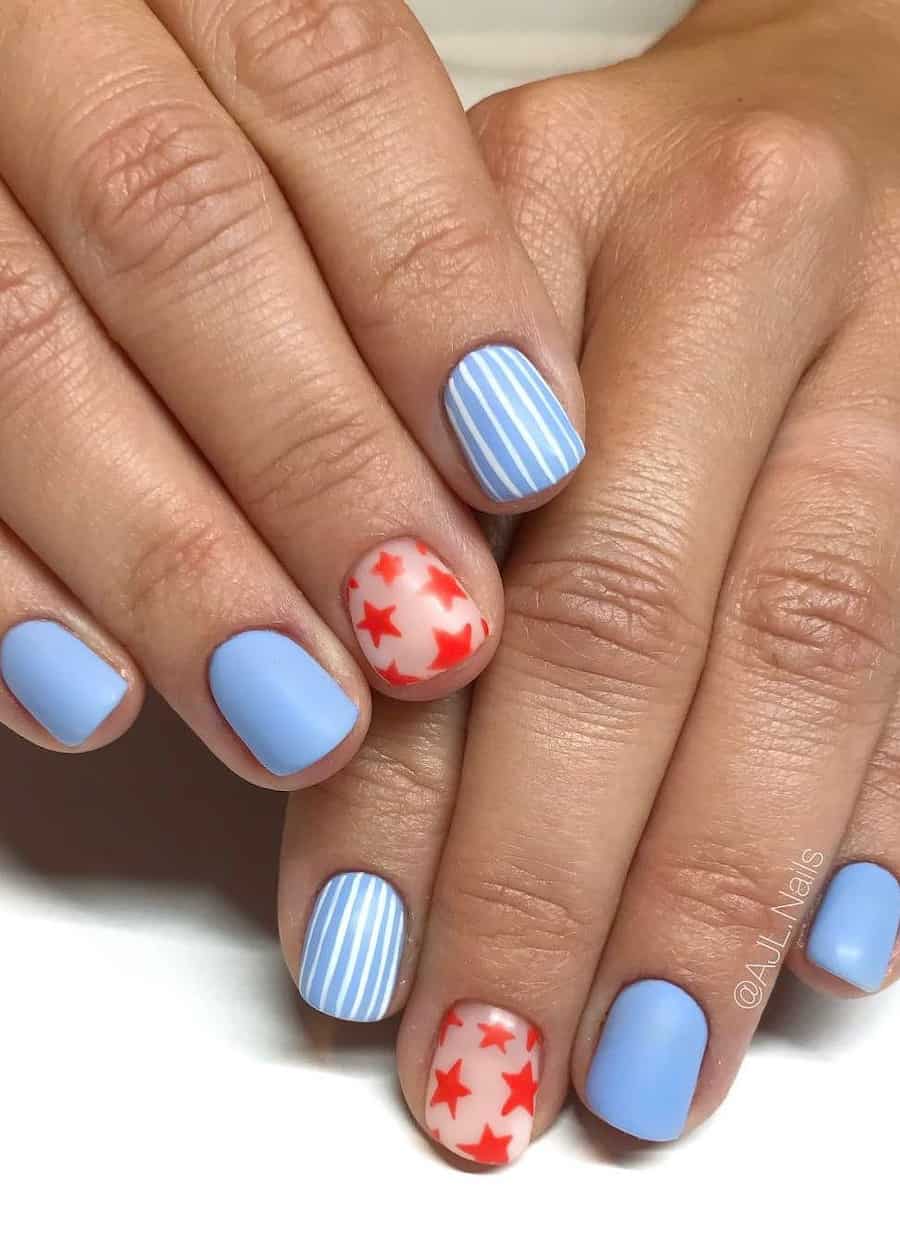 short square nails painted a pastel blue featuring a striped accent nail and another accent nail with nude polish and red stars