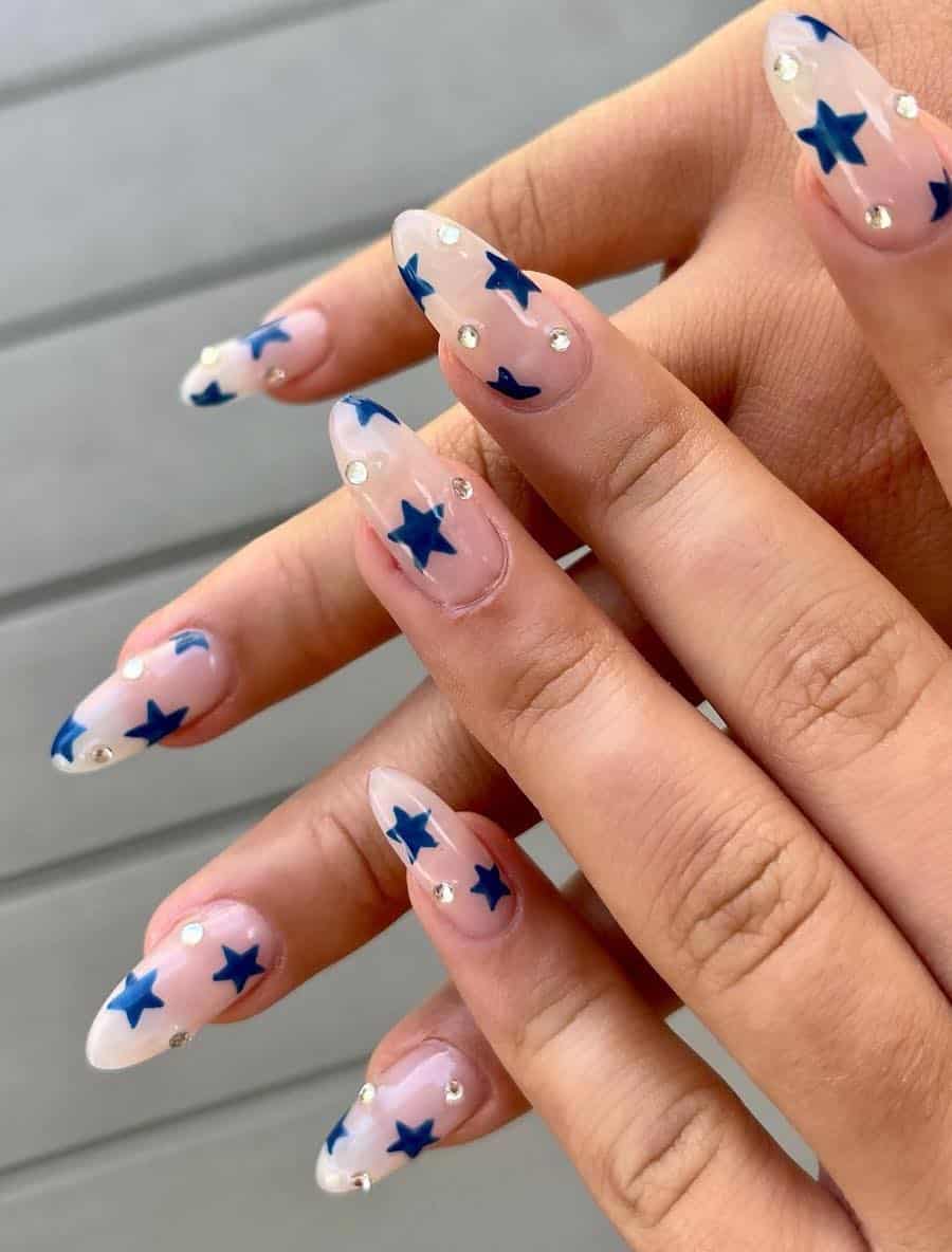 long milky white almond nails with dark blue stars and gems