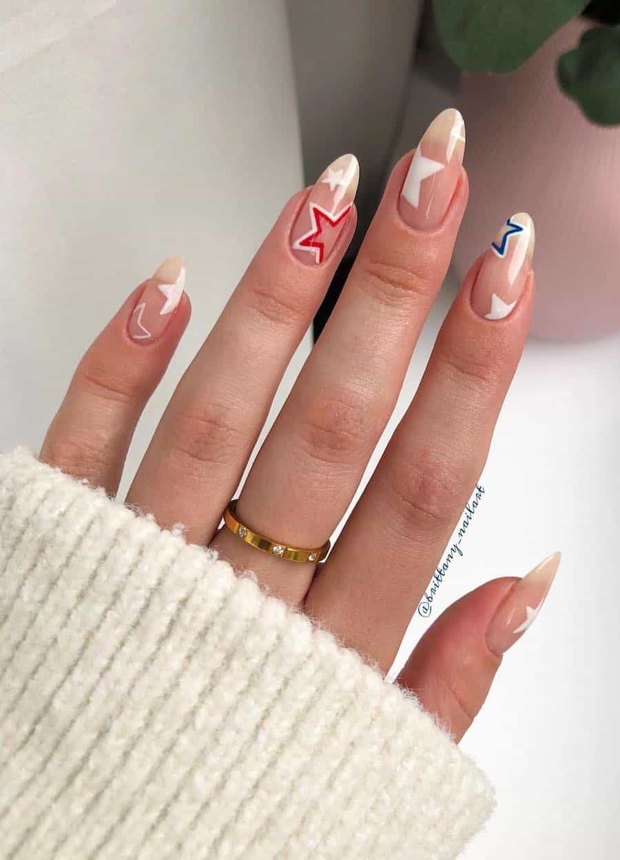 long nude almond nails with white stars and red and blue accent stars