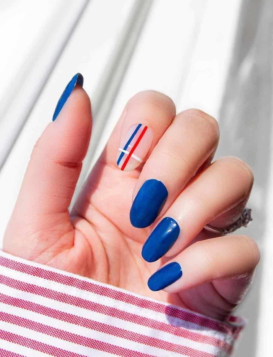 long round blue nails with a nude accent nail featuring red, white, and blue strips