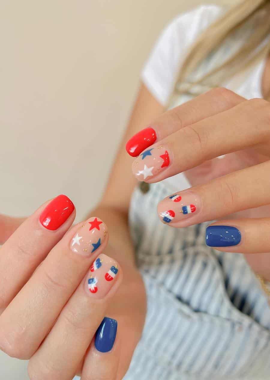 short squoval nails painted with red and blue polish and nude accent nails with stars and popsicle nail art