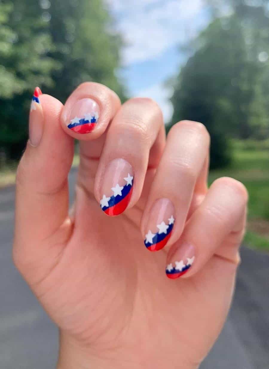 short round nails with asymmetrical red and blue tips with white star accents
