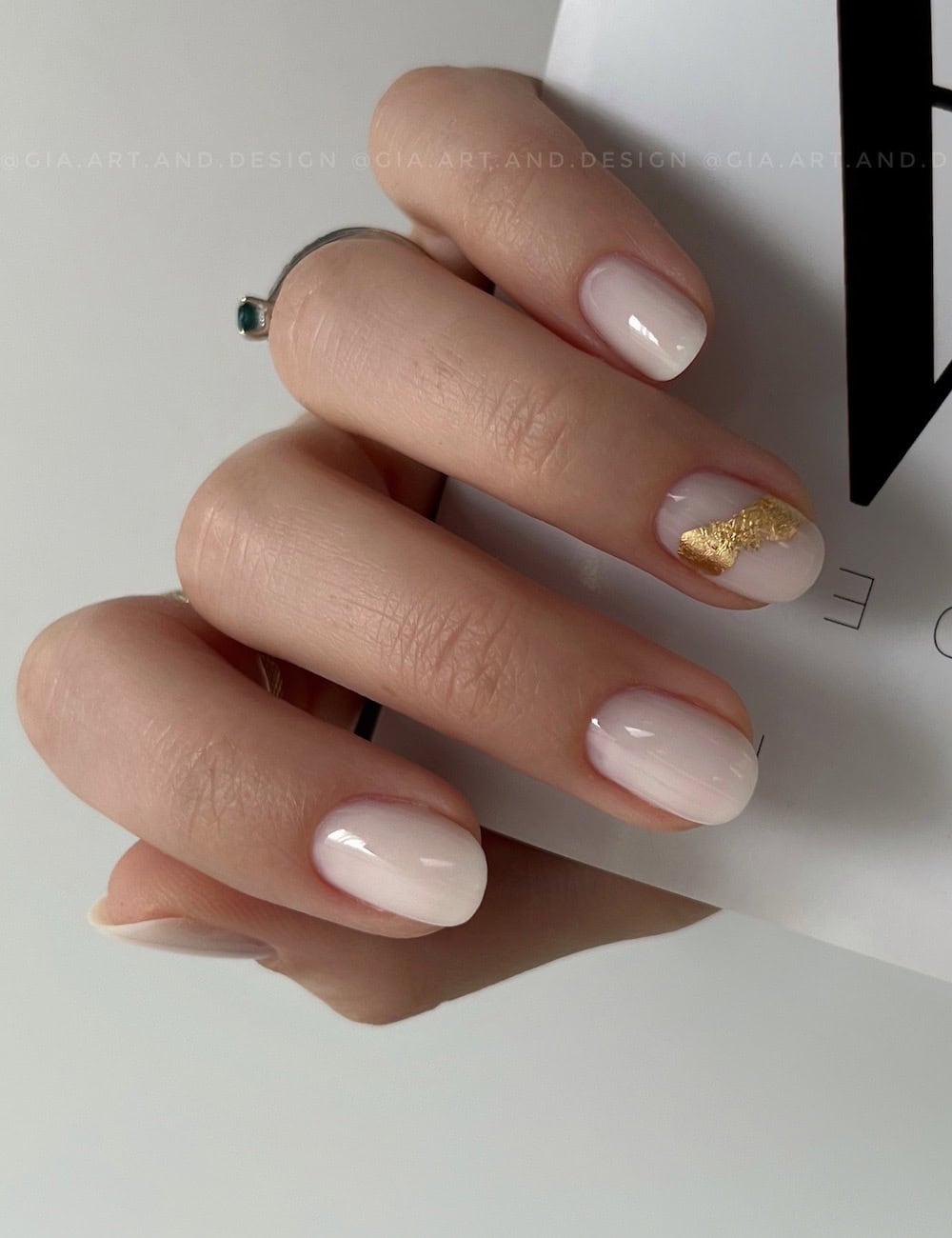 short round milky white nails with a gold foil accent nail