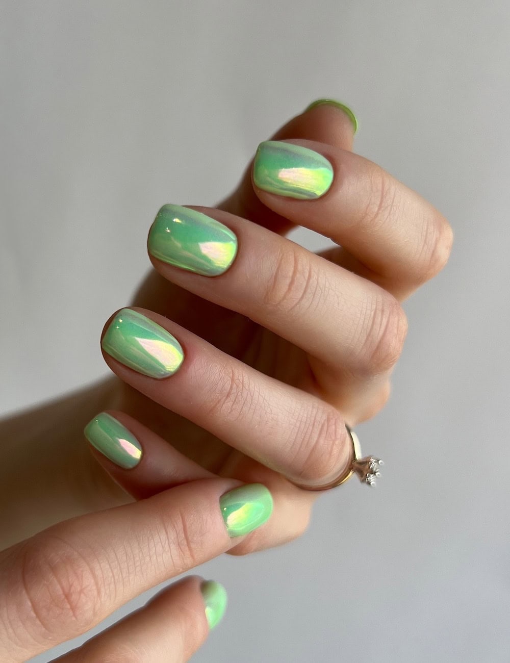 short squoval nails with a lime green polish and chrome finish