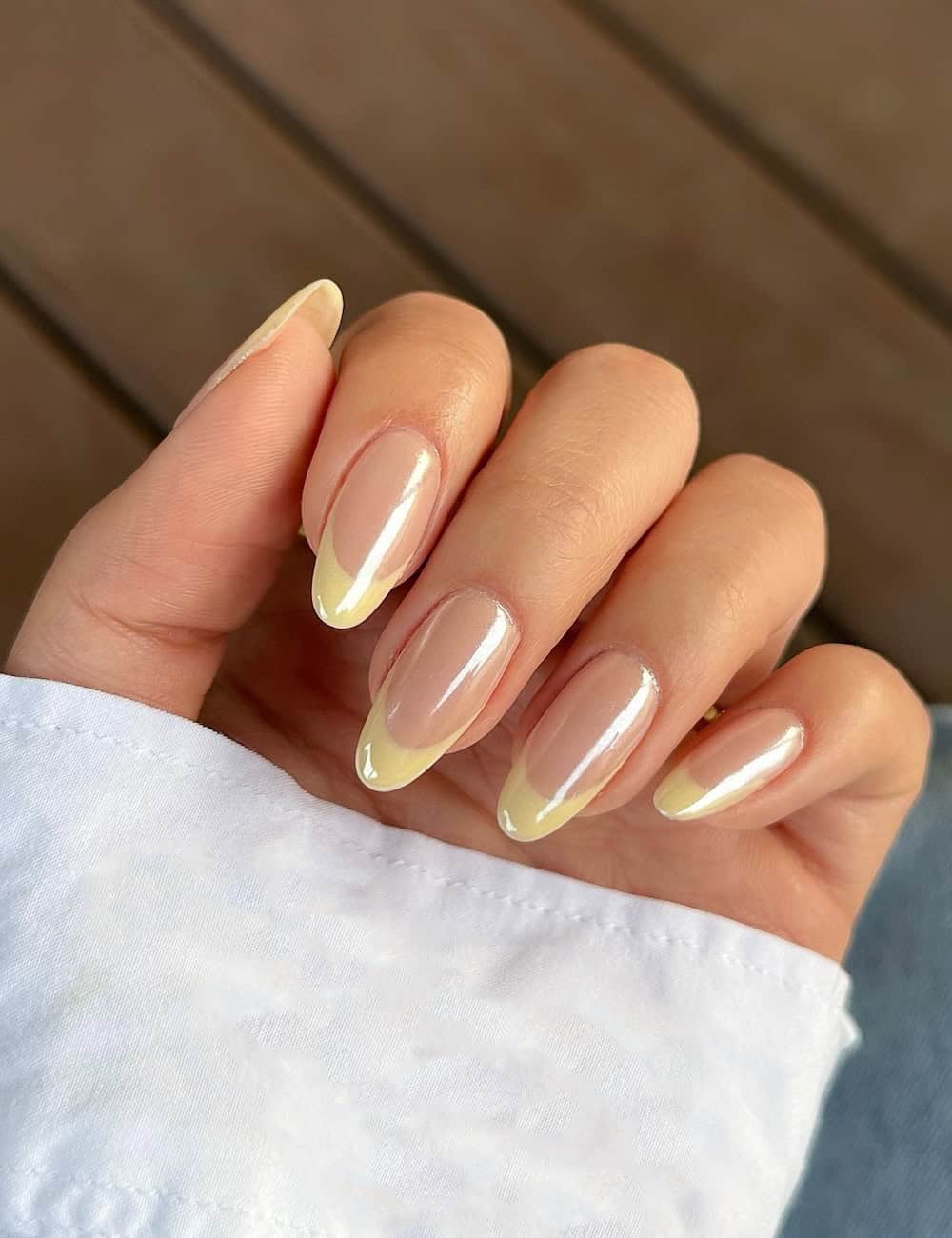 medium nude almond nails with butter yellow tips and a chrome finish