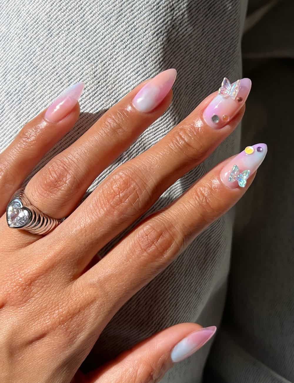 medium almond nails with soft pastel marbling, butterfly charms, and colorful crystal accents
