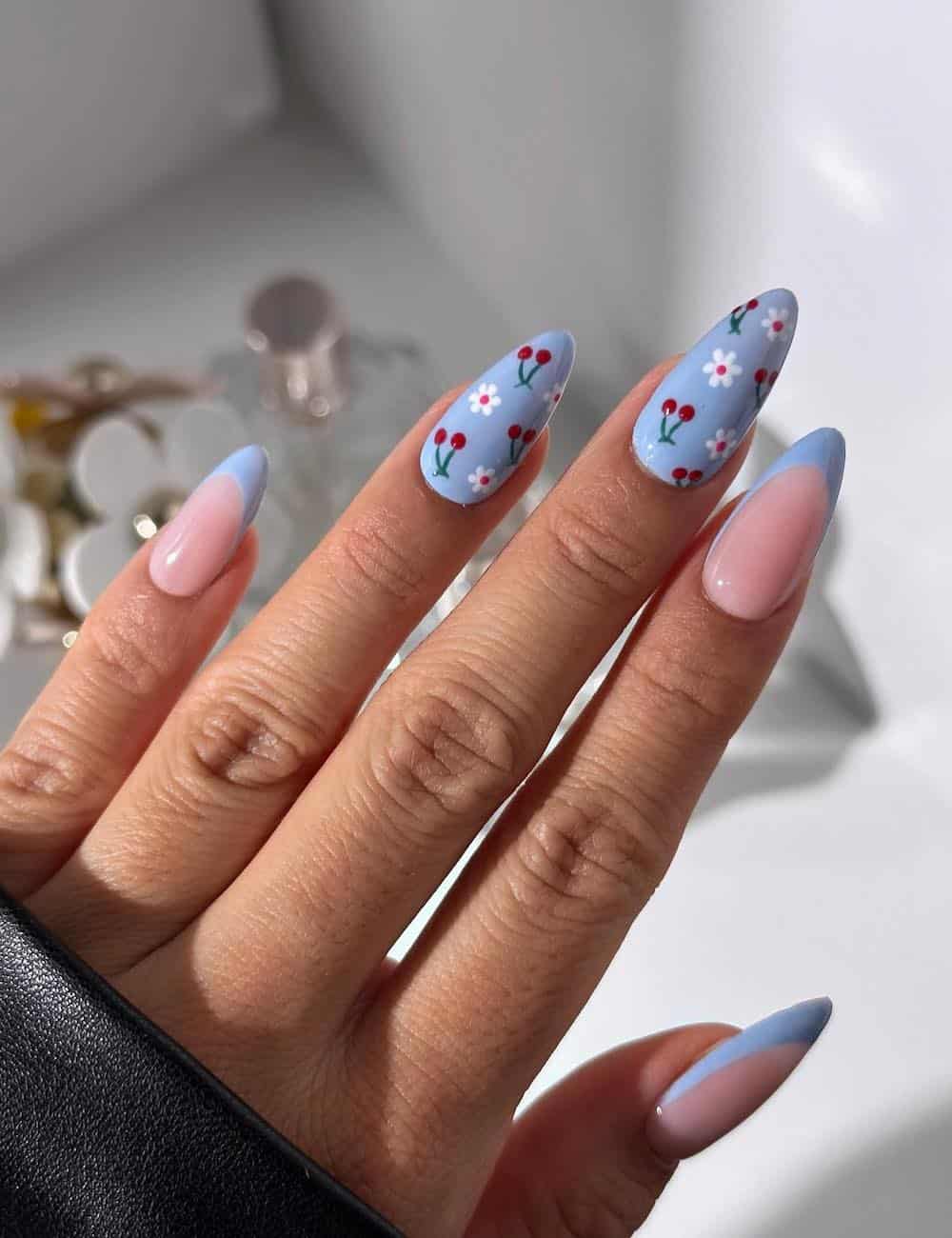 medium nude almond nails with baby blue tips and baby blue accent nails with cherry and floral nail art