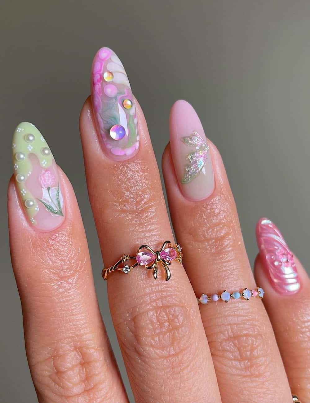 long almond nails with pink, purple, and green polish featuring 3D fairy nail art