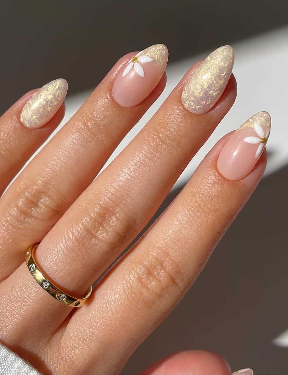 medium almond nails with a pearly yellow finish and french tip accent nails with floral art