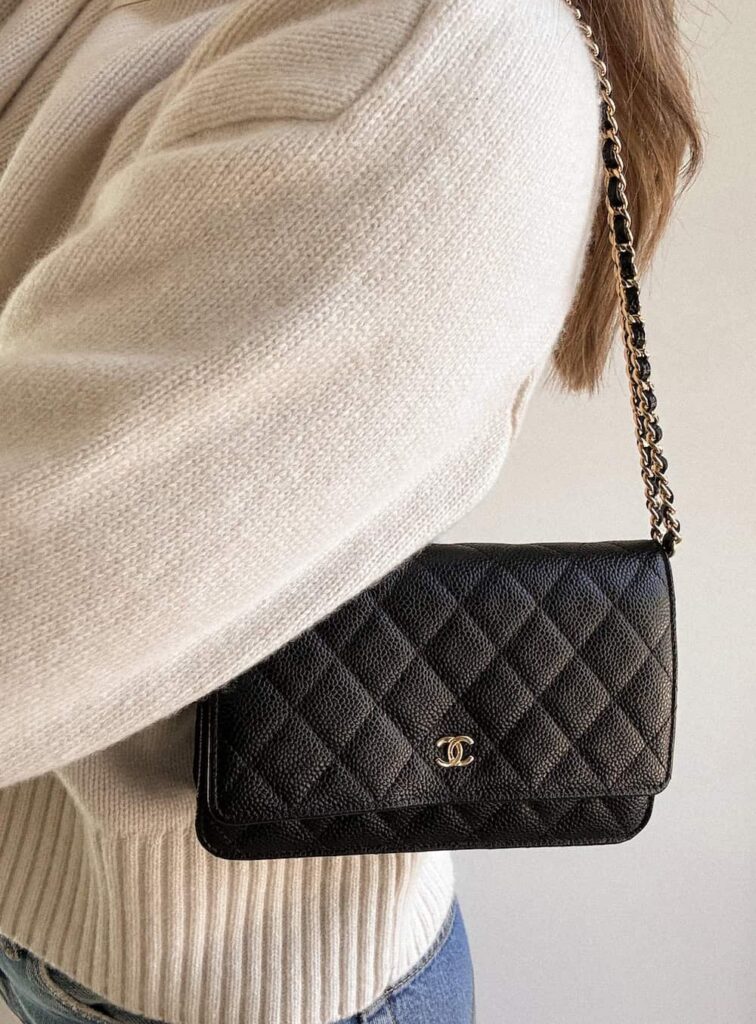 woman holding a black Chanel wallet on chain