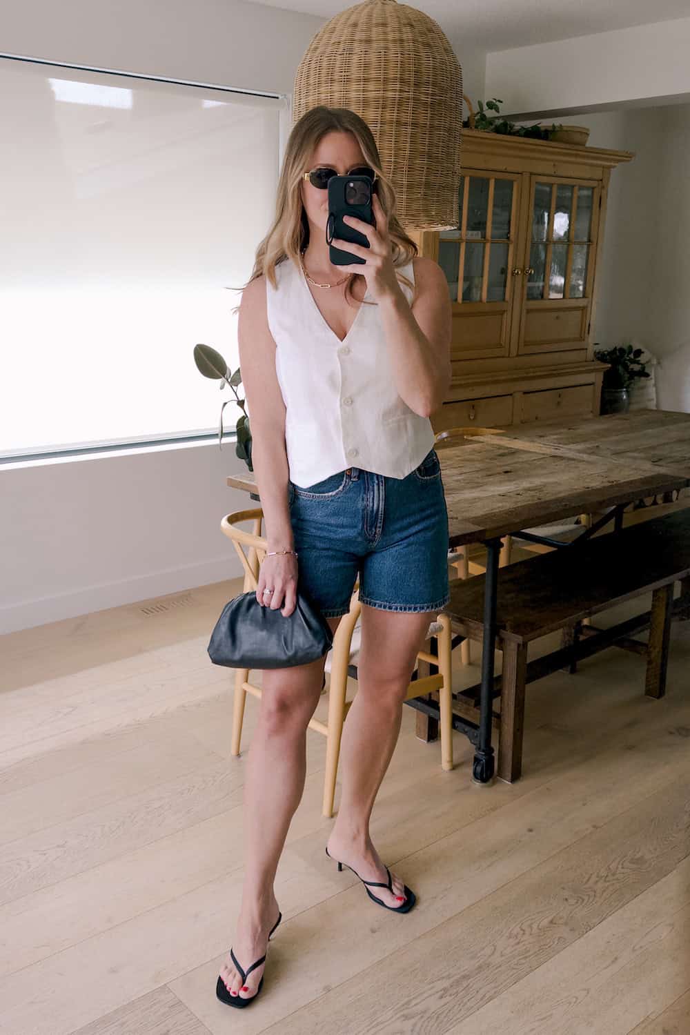 Christal wearing denim shorts with a white vest top and black sandal heels.