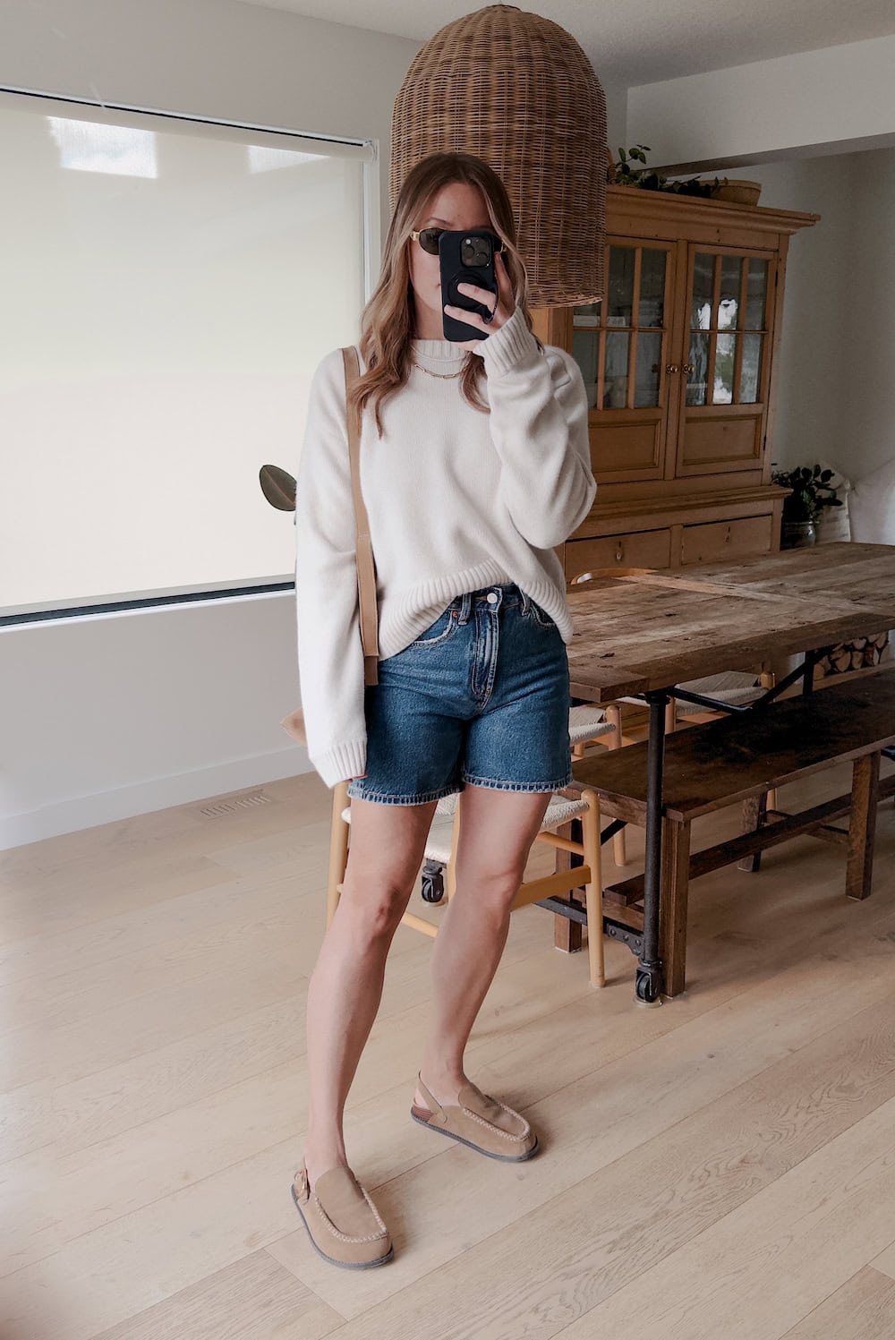 Christal wearing denim shorts with a white sweater and cozy shoes.