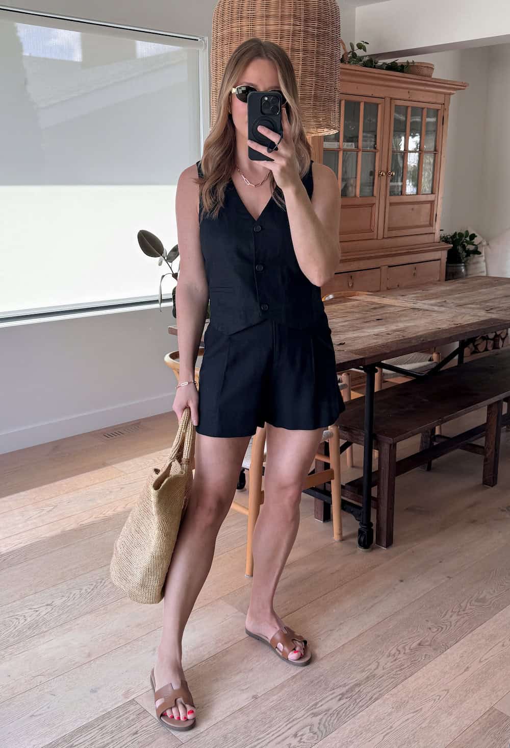 Christal wearing black shorts with a black vest top and brown sandals.