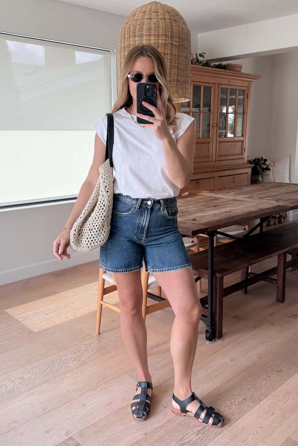 Christal wearing denim shorts with a white t-shirt and black sandals.