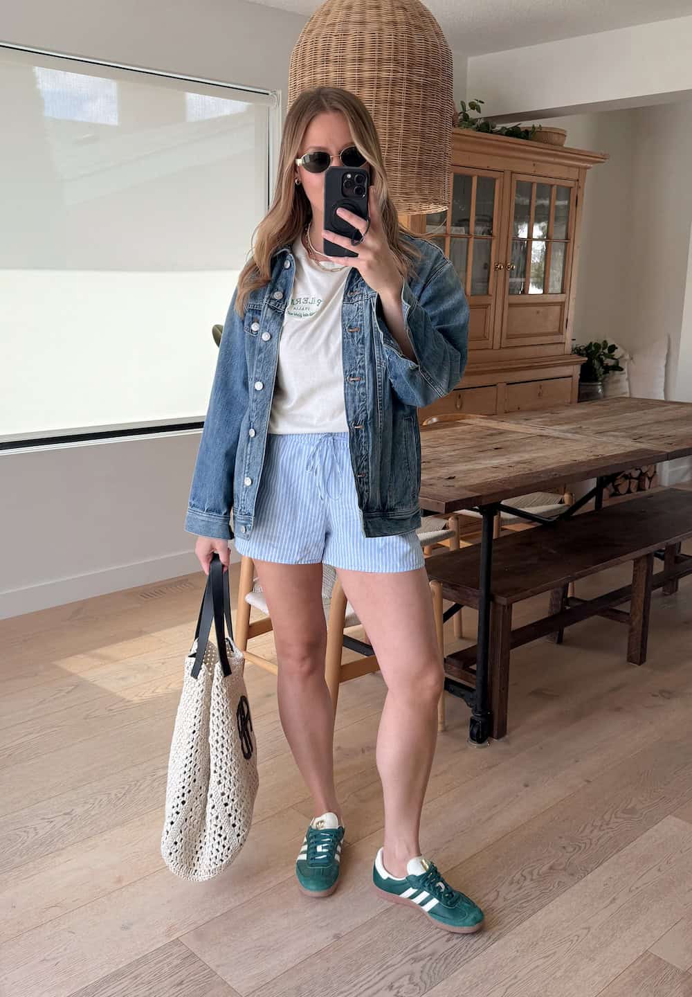 Christal wearing white and blue striped shorts, a t-shirt and a denim jacket with green sneakers.