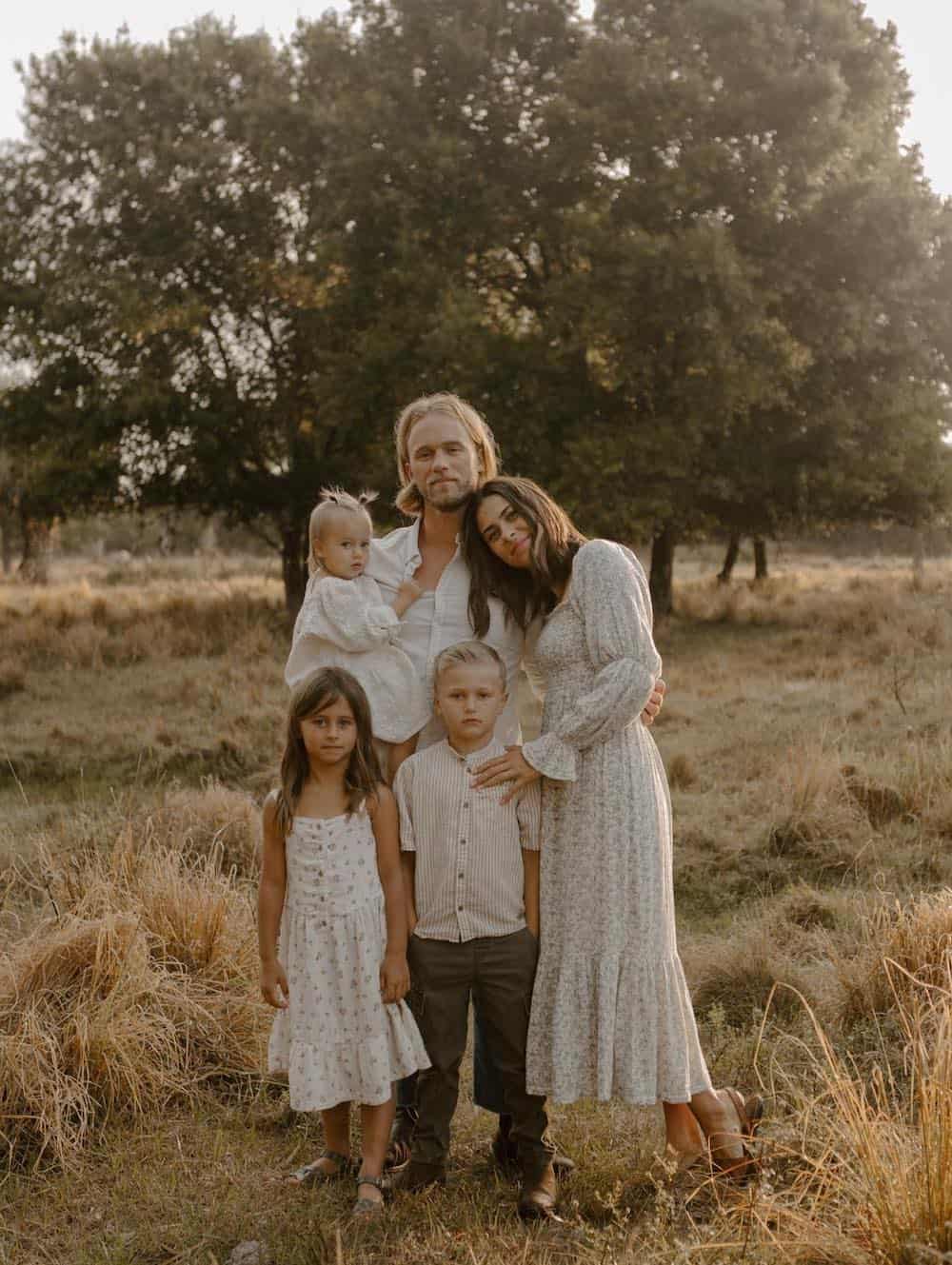 a family portrait featuring neutral outfits, floral prints, and dresses for the mom and girls