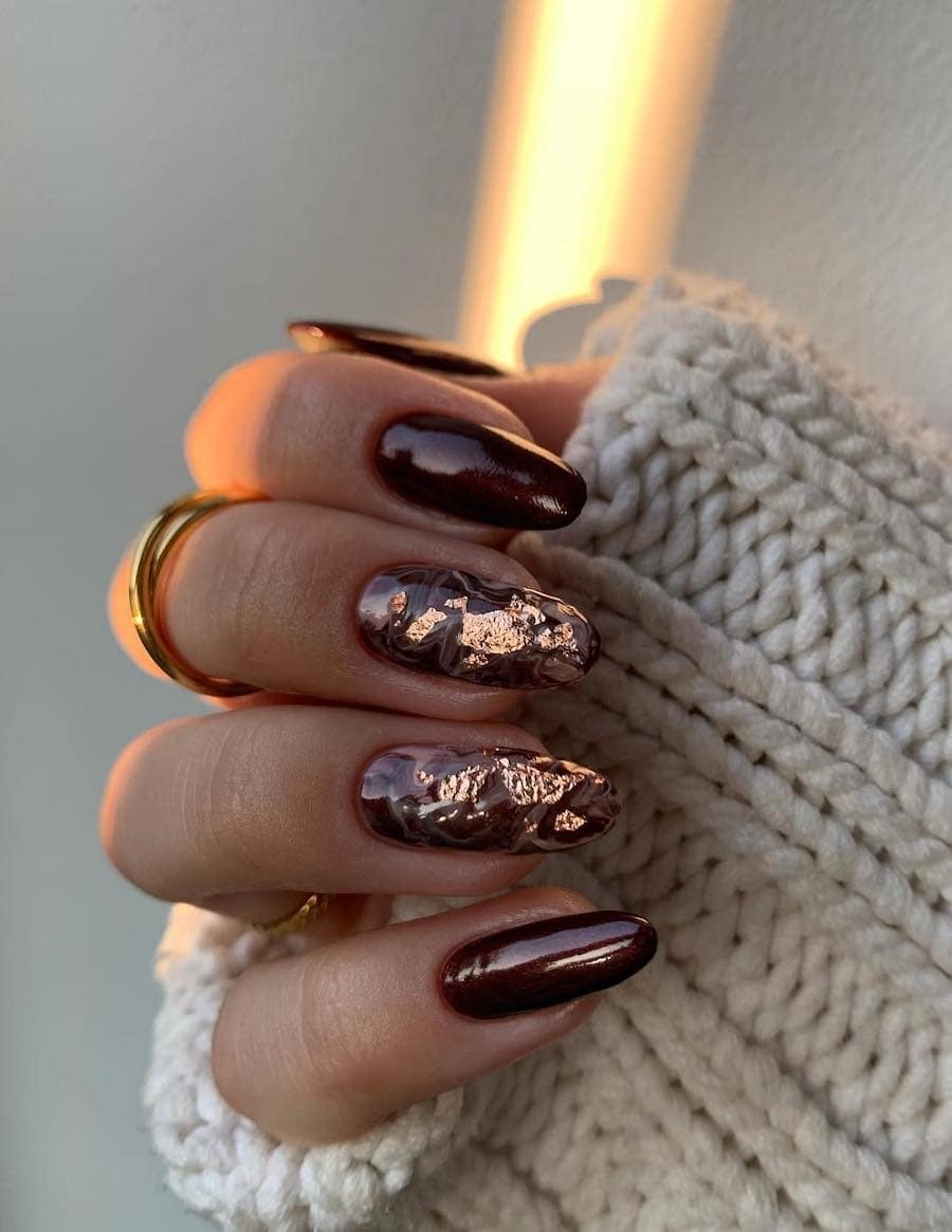 long brown almond nails with marbled accent nails featuring gold foil accents