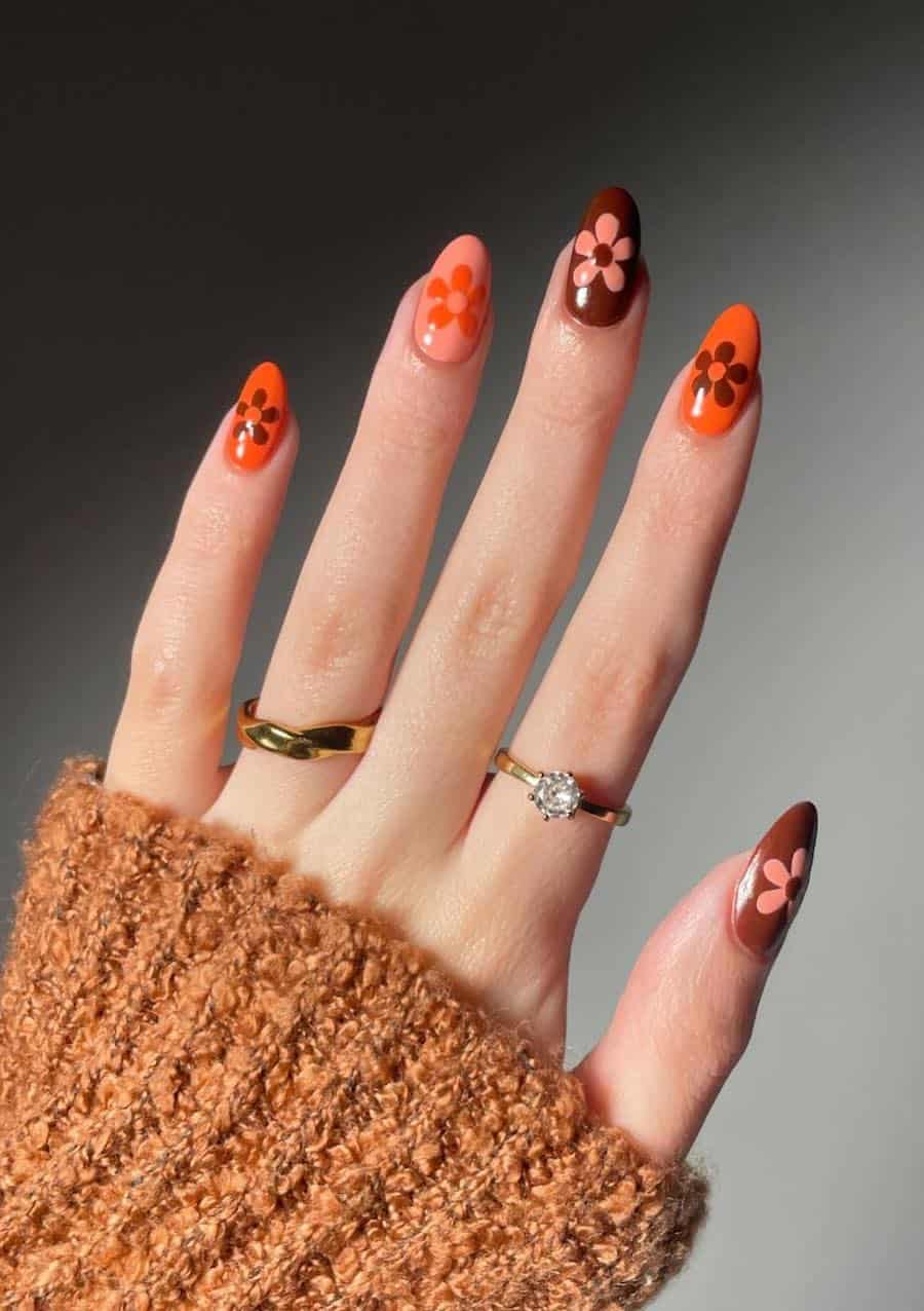 short almond nails featuring peach, orange, and brown nail polish with retro flowers