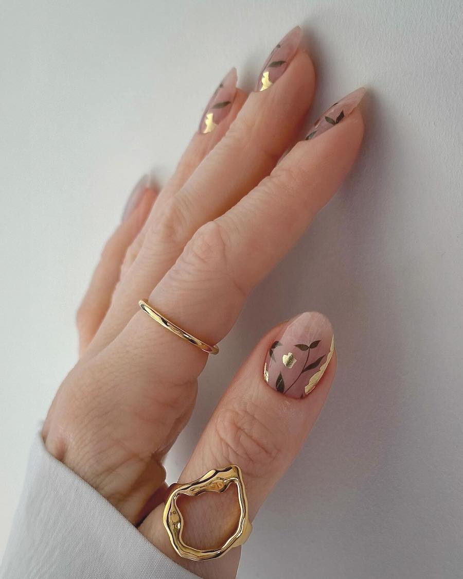 short glossy nude round nails with delicate green botanical art and gold foil accents