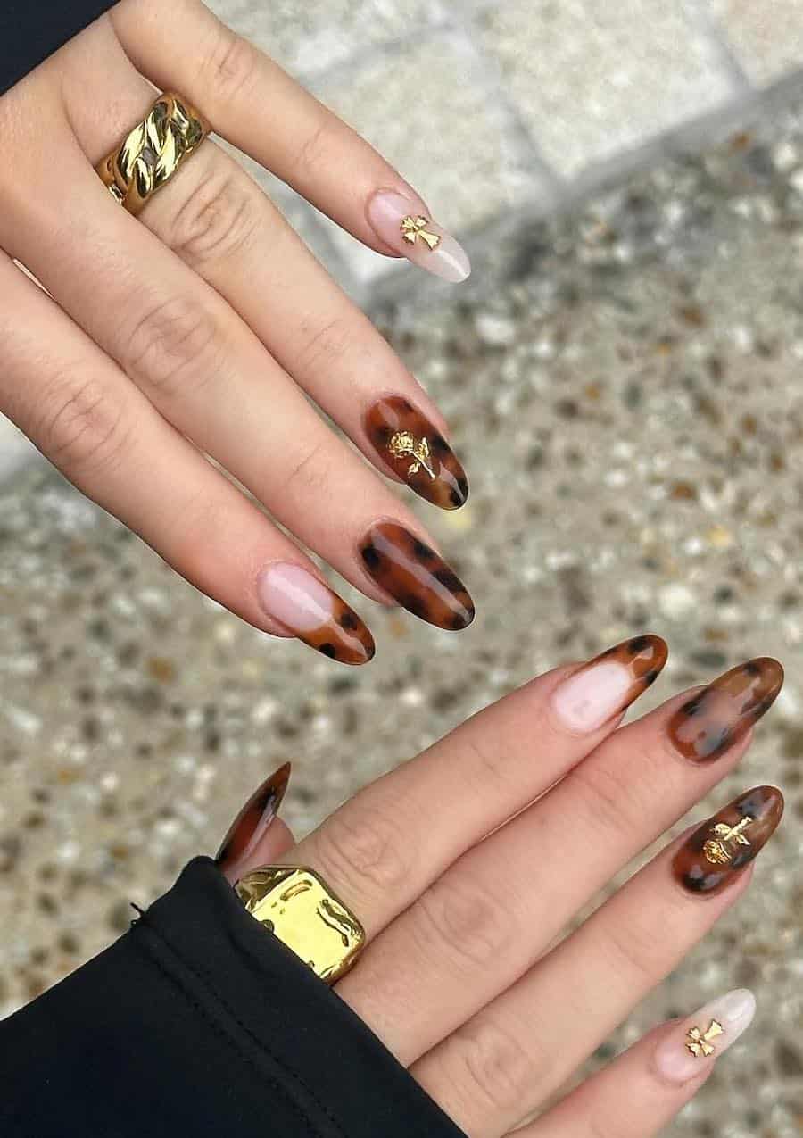 long almond nails featuring classic tortoise shell print and nude accent nails with tortoise shell tips and gold charm accents